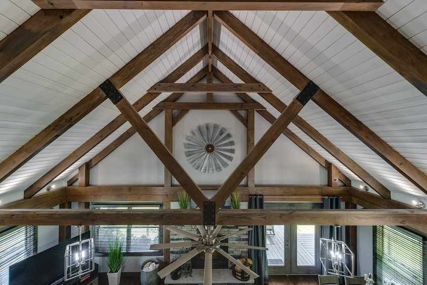Photo taken from the open second floor showing the detail of the painted wood ceiling and exposed beams in a contemporary log home
